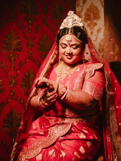 A portrait of my Bengali bride Shubhashree, looking radiant in her red saree. The golden glow makeup complements her traditional jewelry perfectly.