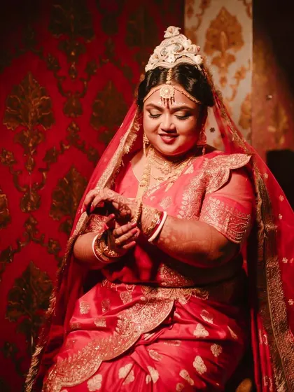 A portrait of my Bengali bride Shubhashree, looking radiant in her red saree. The golden glow makeup complements her traditional jewelry perfectly.