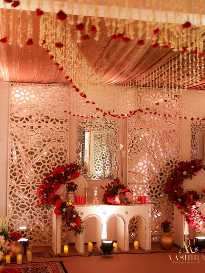 A wider view of the event space, showing how the intricate white jali panels, red floral arrangements, and hanging tuberose garlands came together to create a cohesive, elegant design.