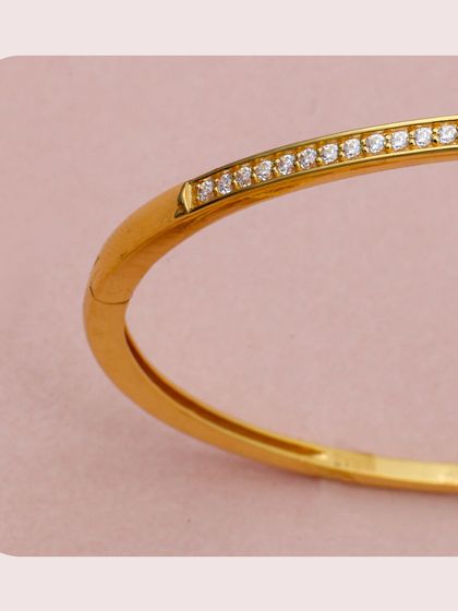 A close-up of a gold kada inspired by the classic nail bracelet design, featuring a line of sparkling diamonds. This piece is the epitome of modern luxury and a must-have for fashion-forward retailers.