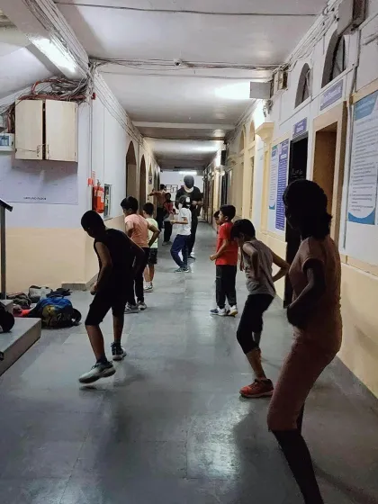 A group of students practices basic fencing stances. Mastering the 'en garde' position and proper posture is crucial for balance and effective movement on the strip.
