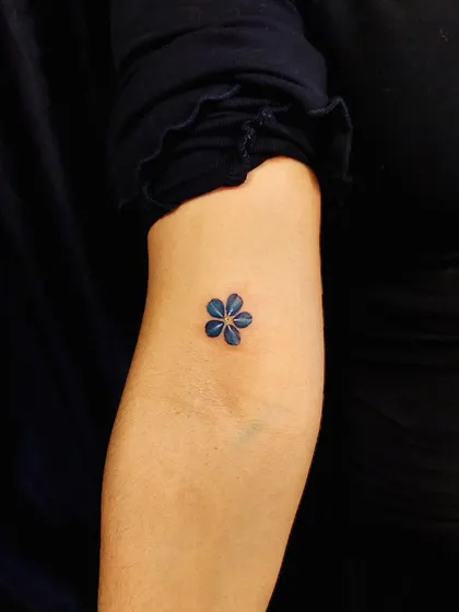 A tiny blue flower, showcasing our ability to work with color in minimalist designs. This piece is a delicate and beautiful statement.
