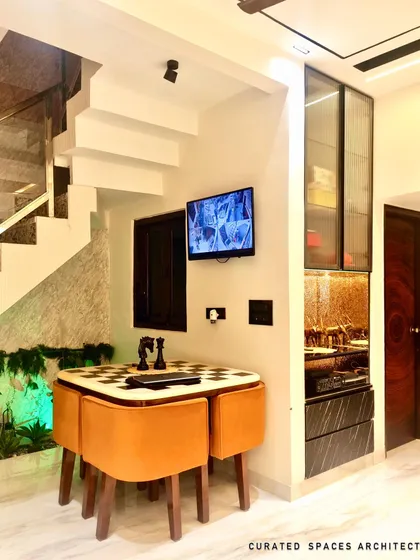 This shot shows the clever integration of a dining nook and a glass crockery unit next to the staircase, proving that every square foot can be utilized with smart residential design.
