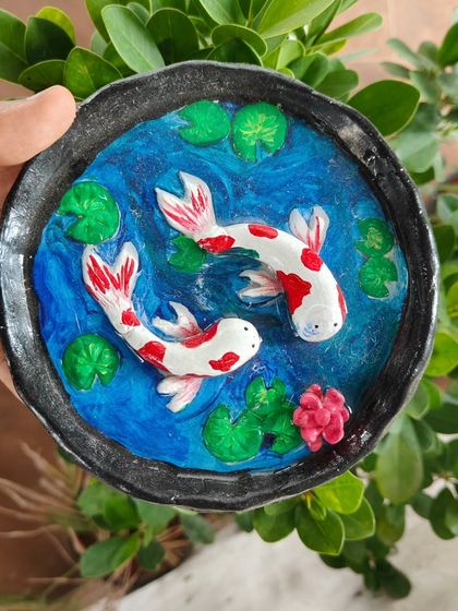 A beautifully detailed koi pond dish made from clay. This is a great example of the intricate and personalized pieces you can create in our hand-building pottery sessions.