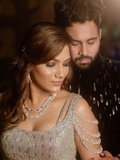 A romantic shot of the couple at their sangeet. The bride's silver, off-shoulder blouse and diamond jewelry are perfectly complemented by her glam makeup.