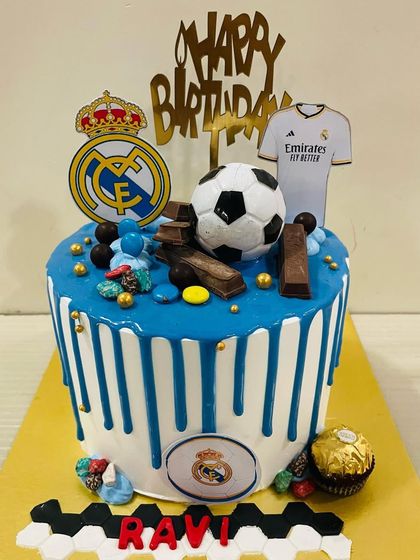 A tall drip cake for a Real Madrid fan, featuring the team logo, a jersey, and a football topper.