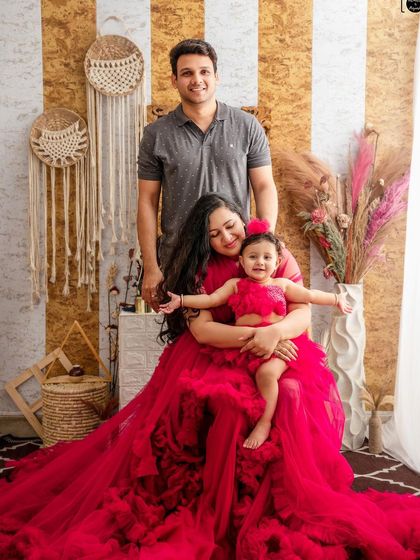 A full family portrait can be added to any baby photoshoot. Here, the father joins the mother and daughter, completing the picture against a warm, boho-themed backdrop.
