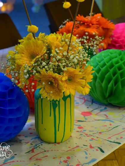 A colorful art-themed centerpiece with paint-drip jars and honeycomb paper balls.