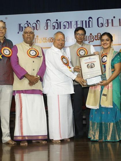 A group photo on stage with the dignitaries after being awarded the 'ISAI CHUDAR' title by Kartik Fine Arts.