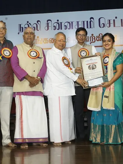 A group photo on stage with the dignitaries after being awarded the 'ISAI CHUDAR' title by Kartik Fine Arts.