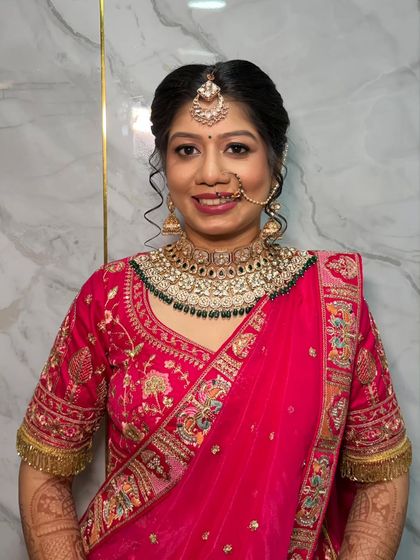 A happy, smiling portrait of the bride. Her makeup is fresh and radiant, with a classic nath and bindi completing her traditional wedding look.