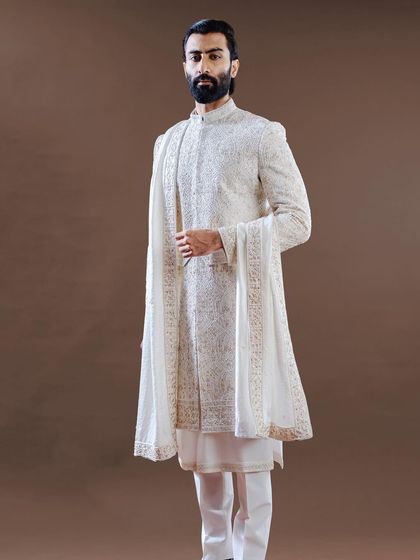 The purity of white is elevated with fine, gold-toned embroidery in this elegant sherwani. Paired with a matching stole, this ensemble is a perfect example of classic design and meticulous bespoke fitting.