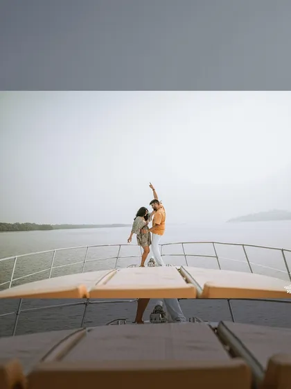 A creative shot from the deck of a yacht, capturing the couple dancing against the open water, showcasing a fun and dynamic pre-wedding session.
