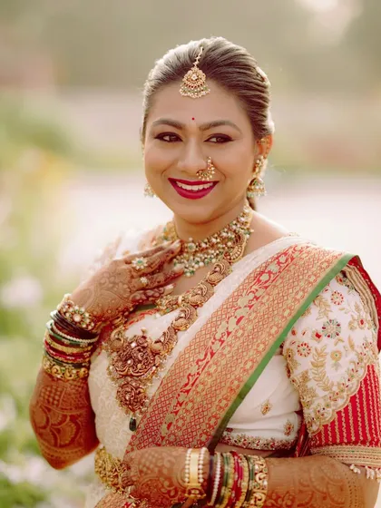 A close-up portrait of a bride on her special day. The custom blouse I designed features intricate embroidery that matches the border of her saree and complements her beautiful temple jewelry.