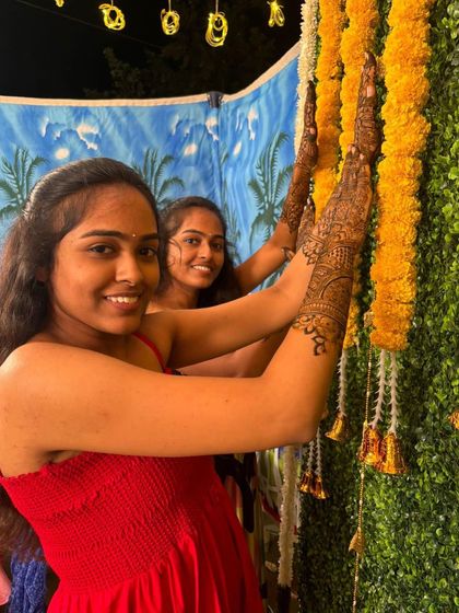 Happy clients posing with their intricate henna at a festive event.