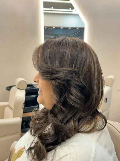 A side profile of a fresh hair color, showing how the face-framing layers and soft curls complement the new shade and bring out the client's features.