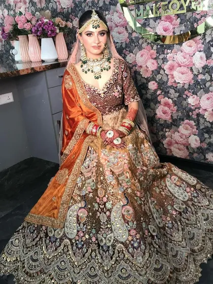 A full view of a bride in a multi-panel lehenga with peacock motifs, a very unique and artistic piece.