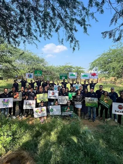 The full team of 40 employees from Bacardi poses with signs after their successful planting drive, where they planted 625 native saplings to help the forest heal.