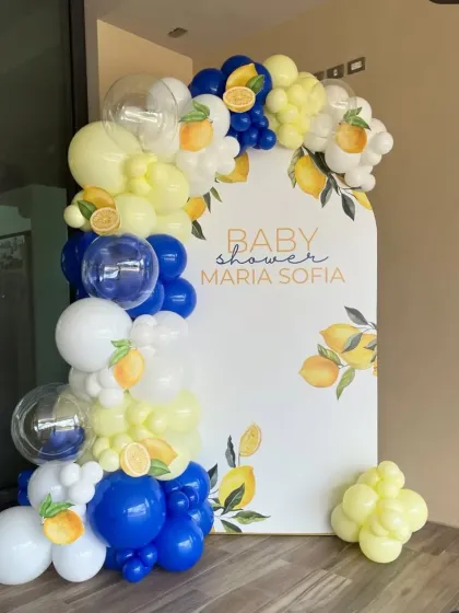 A beautiful lemon-themed baby shower for Maria Sofia. The decoration features a custom backdrop with a lemon print, framed by a balloon garland in royal blue, yellow, and white.