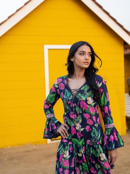 A medium shot from the Tangerine Tiger campaign, using a bright yellow wall as a contrasting backdrop for the floral dress.
