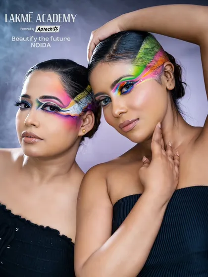 A powerful portrait of two models with matching creative eye makeup. The rainbow colors and graphic hair detail create a stunning and cohesive look.