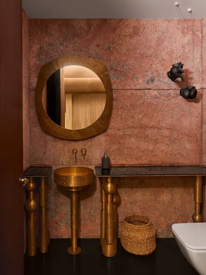 This powder room at the Baid Residence is a showcase of brass craftsmanship. The pedestal wash basin, console, and mirror are all custom-made by Viya Design, set against a rich, red-hued marble wall.