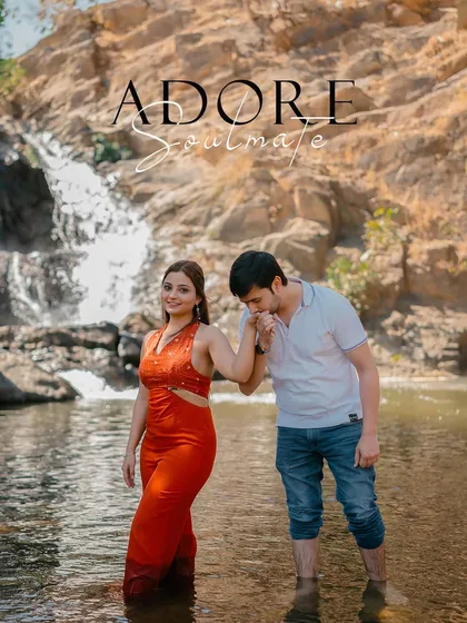 A chivalrous moment as the groom kisses the bride's hand, set against the beautiful scenery of a waterfall.