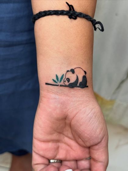 A small, charming tattoo of a panda, chosen by a client as her favorite animal. This piece was part of a larger session celebrating sisterhood, where each sister got tattoos that were personally meaningful.