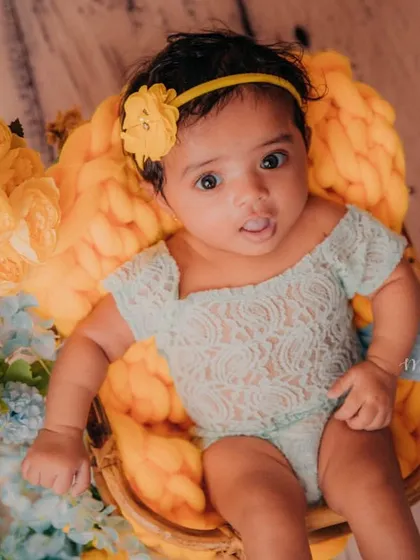 Sitting up like a pro in her little basket. The combination of yellow and blue flowers adds a beautiful, soft touch to this milestone photo.