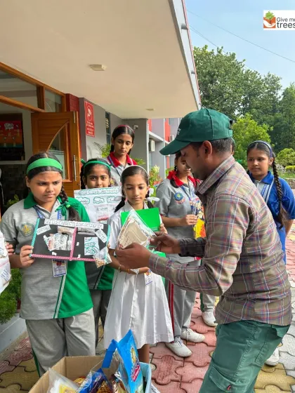 Our team member receives collected seeds and polybags from students. This interaction makes the children feel that their contribution is valued and important.