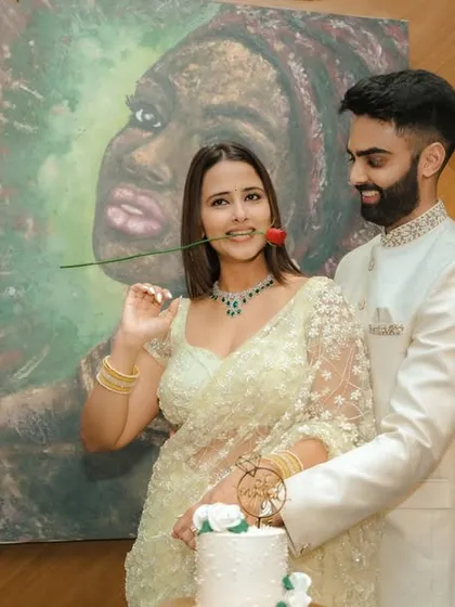 A joyous cake-cutting moment during an indoor engagement celebration in Pune. The couple's happiness is the focus, framed by modern decor and a beautiful piece of art, capturing the celebratory spirit of the occasion.
