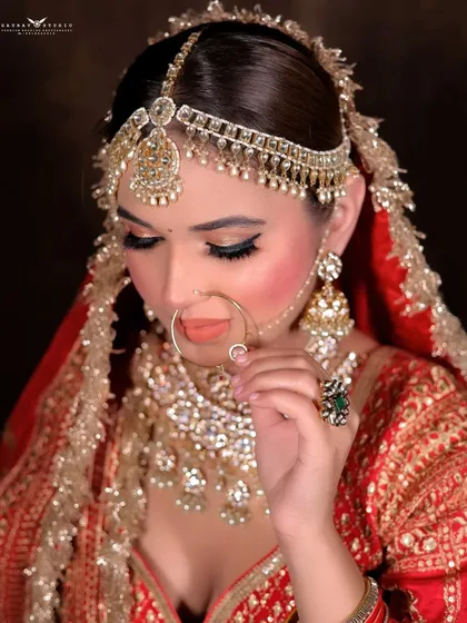 A delicate pose with the bride adjusting her nose ring, drawing attention to the fine jewelry.