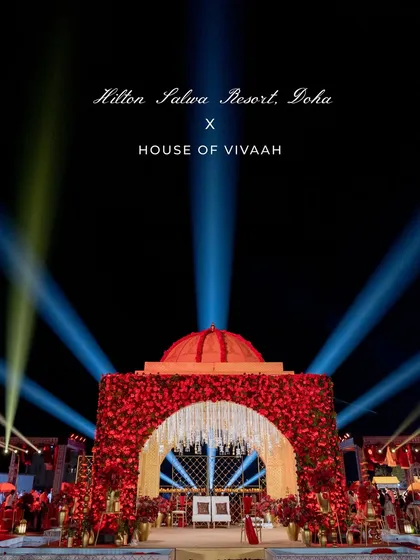 A powerful hero shot of the red floral mandap under dramatic spotlights, with the event's branding, showcasing a pinnacle of our luxury destination wedding design.