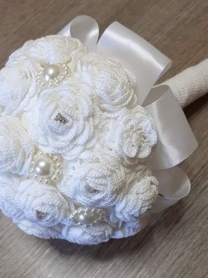 An elegant, all-white bridal bouquet made entirely from crochet. It's adorned with pearls and satin ribbon, creating a timeless keepsake from your special day.
