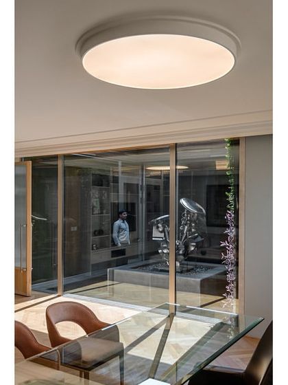 A detail shot of a director's cabin in the Stainless Steel Office, showing the view into the open-to-sky courtyard. The design thoughtfully integrates art and architecture, with a Subodh Gupta sculpture visible from the workspace.