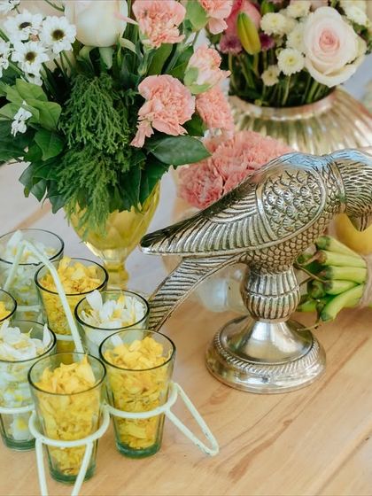 A table detail featuring a silver parrot and small glasses of flowers, adding a touch of Indian heritage to the decor.