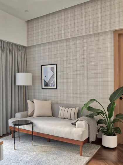 To create a versatile study and entertainment space, I paired functional furniture with comfortable pieces. A cozy sofa set against a plaid wallpaper makes it an ideal lounging spot for relaxed evenings.