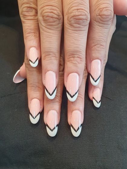 A graphic and modern take on the French manicure. This design on almond-shaped nails uses a sharp, black V-shape to outline the white tip, creating a bold and edgy look.