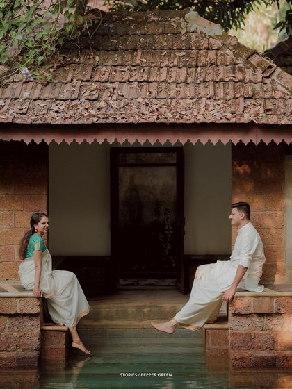 A wide shot of the couple seated on opposite sides of a temple pond, creating a sense of anticipation and connection.