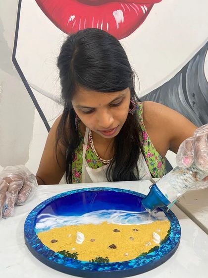 A participant pours resin to create the ocean in her beach art piece. This is where the magic begins.