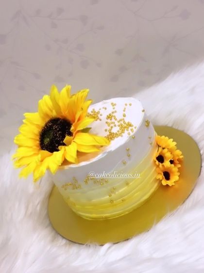 A bright and cheerful cake featuring a beautiful sunflower. The yellow ombre effect on the whipped cream frosting perfectly complements the sunny floral theme.
