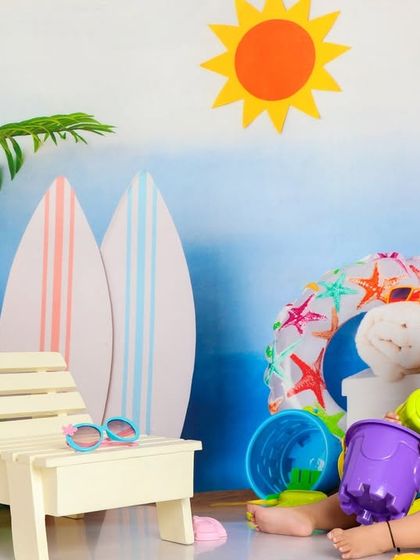 A wide shot of our beach setup, complete with a sun, surfboards, and a flamingo. This little girl is enjoying her day in paradise.