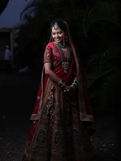 A beautiful, softly lit portrait of the bride. Her smile shines as brightly as her stunning red and gold wedding lehenga.