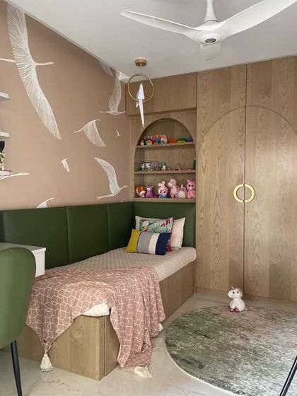 A cozy corner in a girl's bedroom, featuring a built-in bed with a green headboard and storage underneath. The wall is decorated with a beautiful flying birds mural.