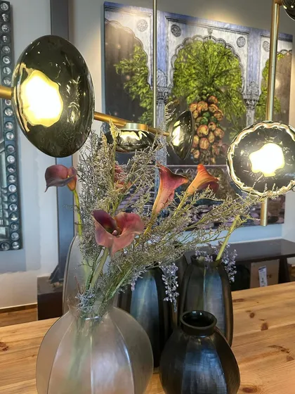 The Ceto chandelier seen through a floral arrangement, creating a soft, layered composition of nature and design.
