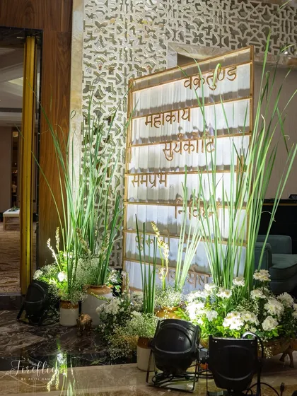 A custom-designed welcome sign featuring Sanskrit verses, surrounded by fresh white flowers and grasses. This element set a spiritual and serene tone for the wedding ceremony.