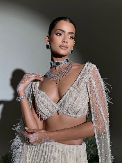 A close-up of the pearl and feather-embellished blouse, a perfect blend of tradition and modern grace.