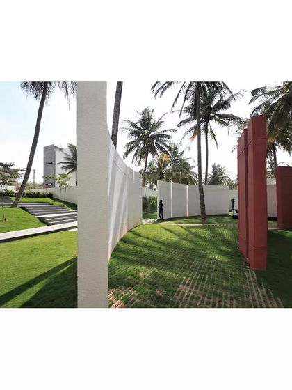 The landscape of the Akriti Experience Centre is defined by curving white walls and bold red planes set amidst lush greenery. This sculptural approach to landscape architecture creates a path of exploration and serendipity for visitors.