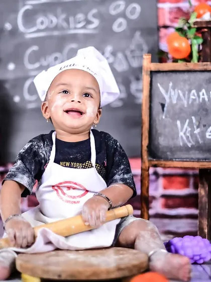 A happy little chef covered in flour, sitting in his personalized "Yuvaan's Kitchen."
