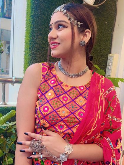 A model looking joyful in a colorful embroidered blouse and oxidized silver jewellery, capturing the spirit of Navratri.